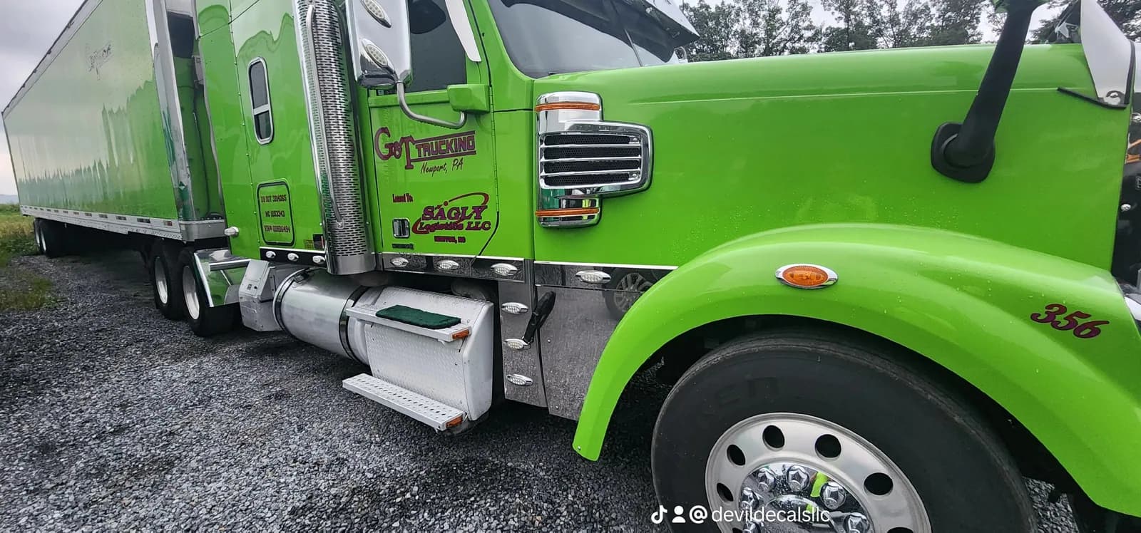 Green commercial dump truck with branded lettering and graphics